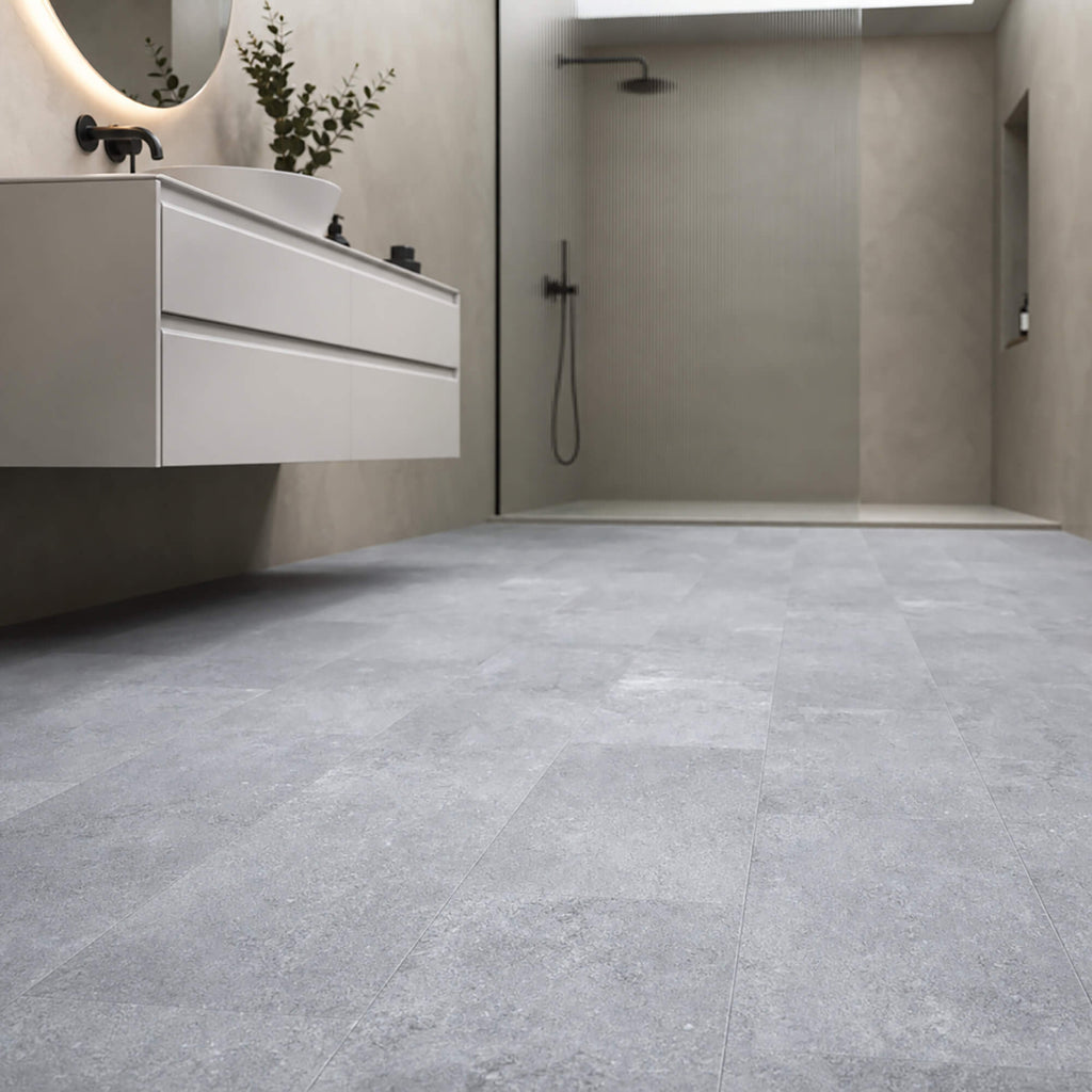 Claros Grey Rigid LVT tile flooring in a bathroom setting with sink and shower area.