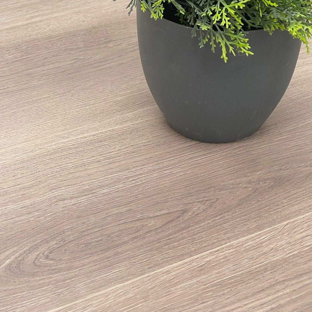 Close-up of Dusky Oak Prestige Plus Laminate Flooring with a plant pot in the background.