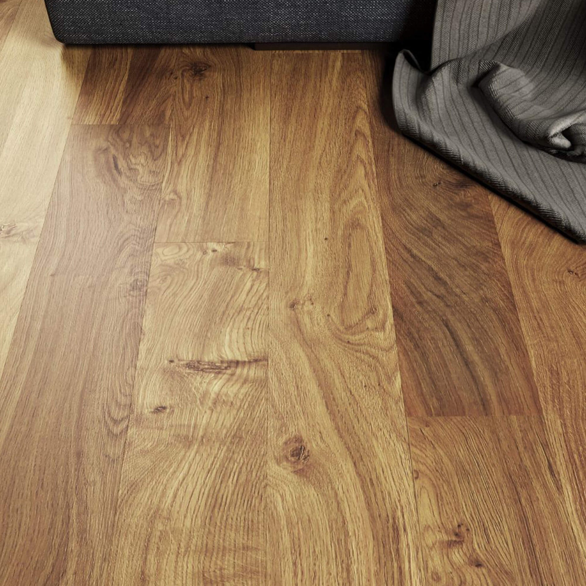 Close-up of Groovy Oak Prestige Laminate Flooring with a sofa and rug in the background.