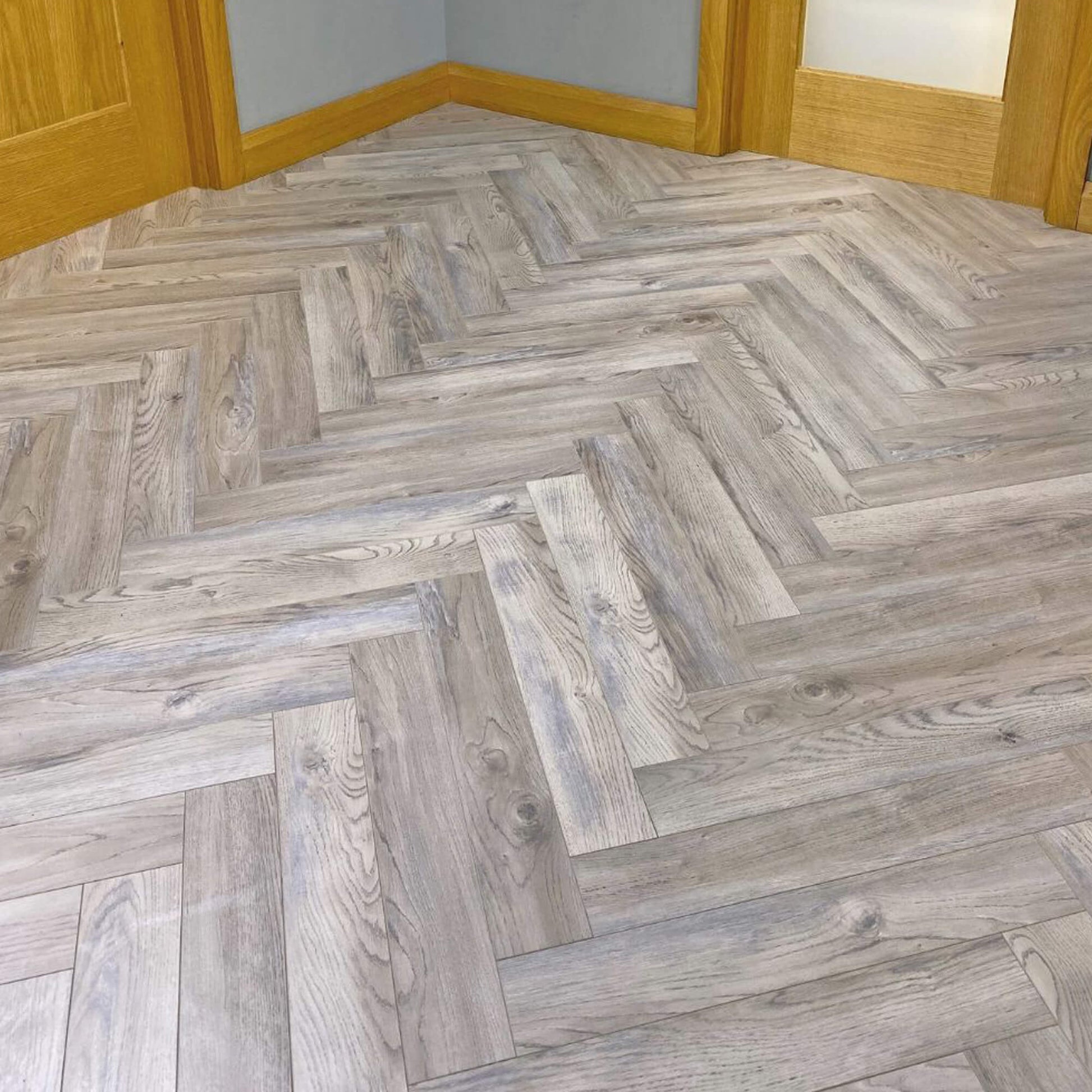 Close-up of Manor Grey Oak Herringbone Laminate Flooring in situ in a hallway setting.