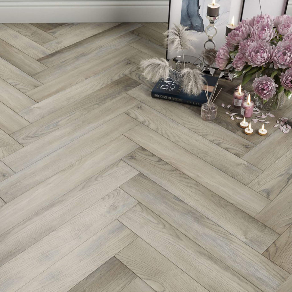 Manor Grey Oak Herringbone Laminate Flooring with home props in the corner.