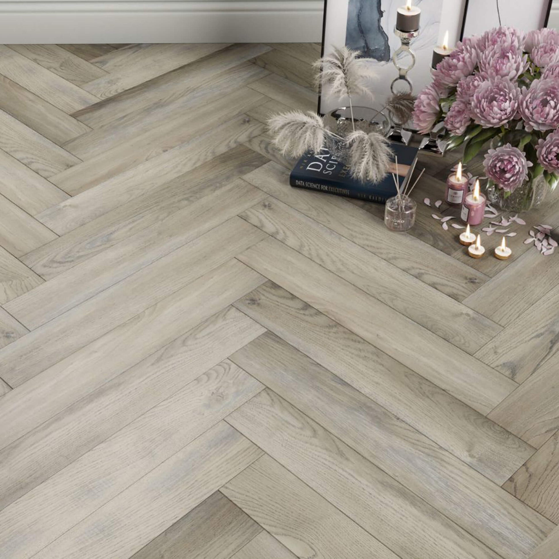 Manor Grey Oak Herringbone Laminate Flooring with home props in the corner.