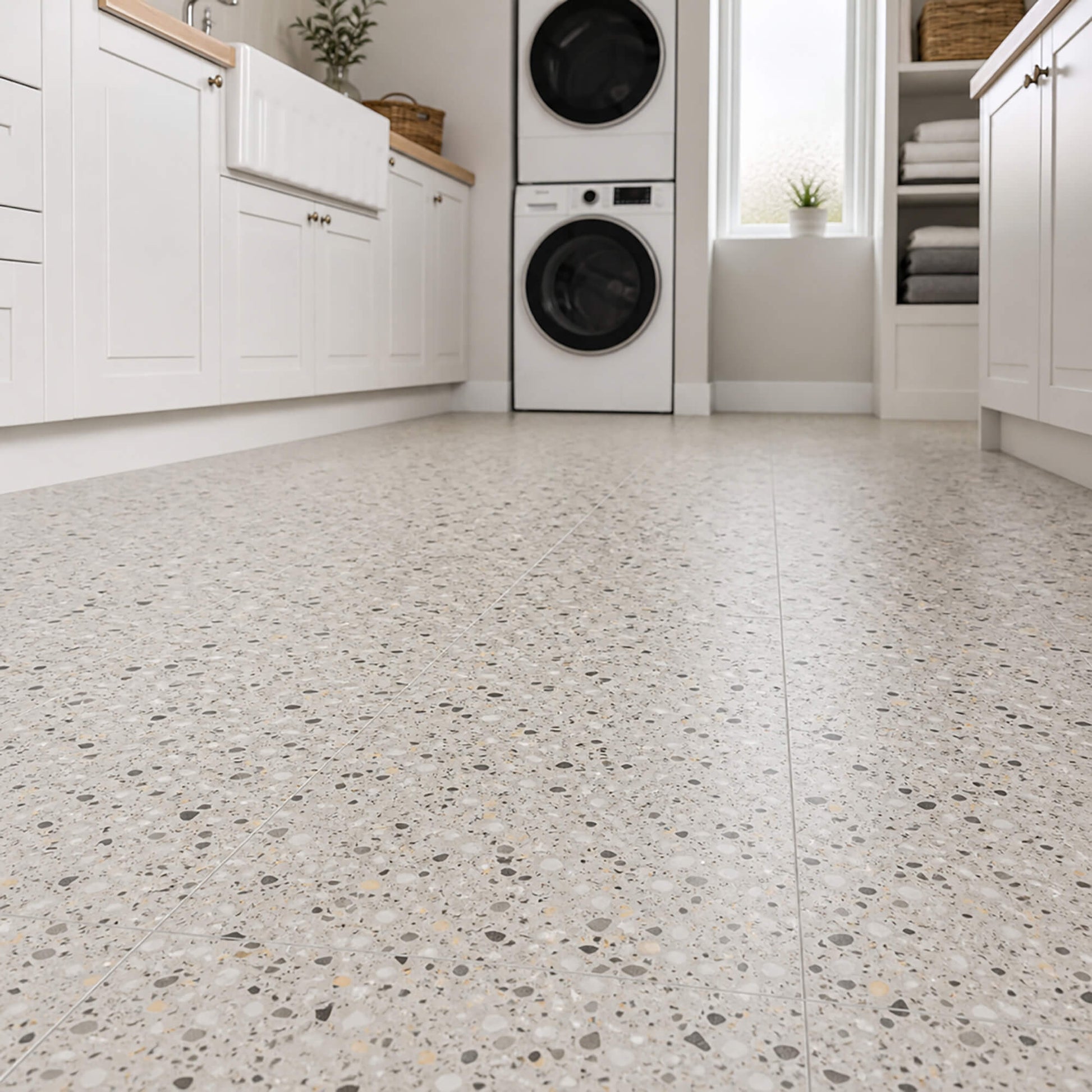 Modern laundry room with white cabinets, washing machines, and a Close-up of Milano Terrazzo Rigid LVT flooring.
