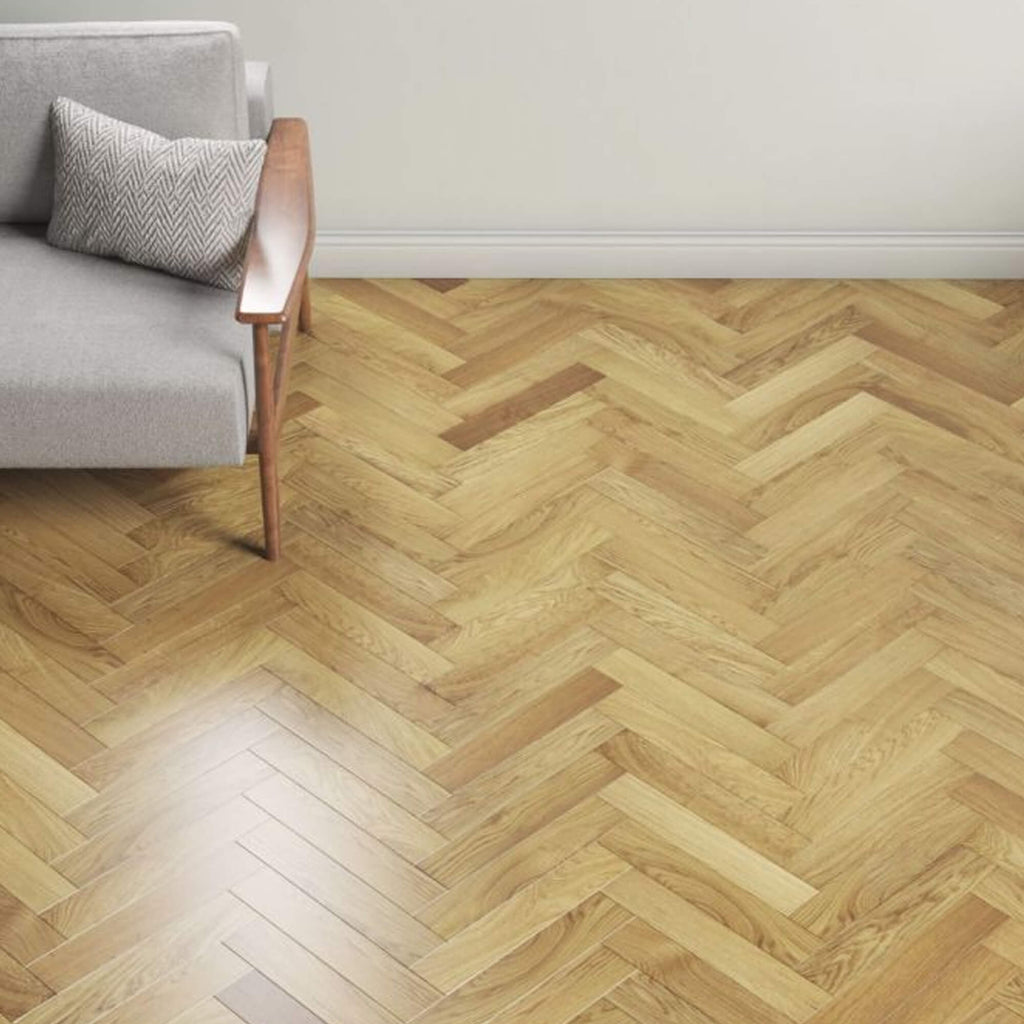 Natural Oak Herringbone Lacquered Engineered Wood Flooring in a room with a grey sofa and wooden armchair.