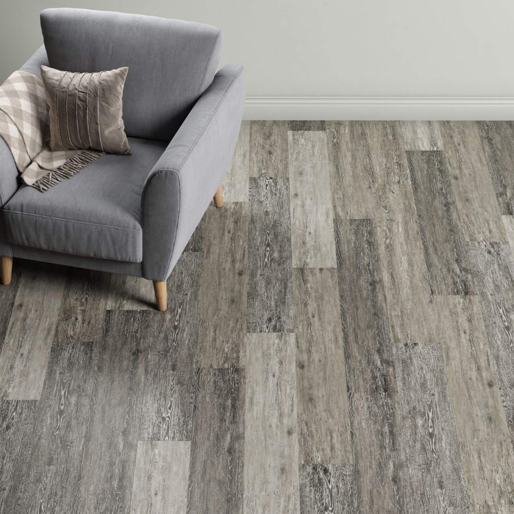 Gray armchair with a textured pillow on a Portland Oak Rigid LVT flooring.