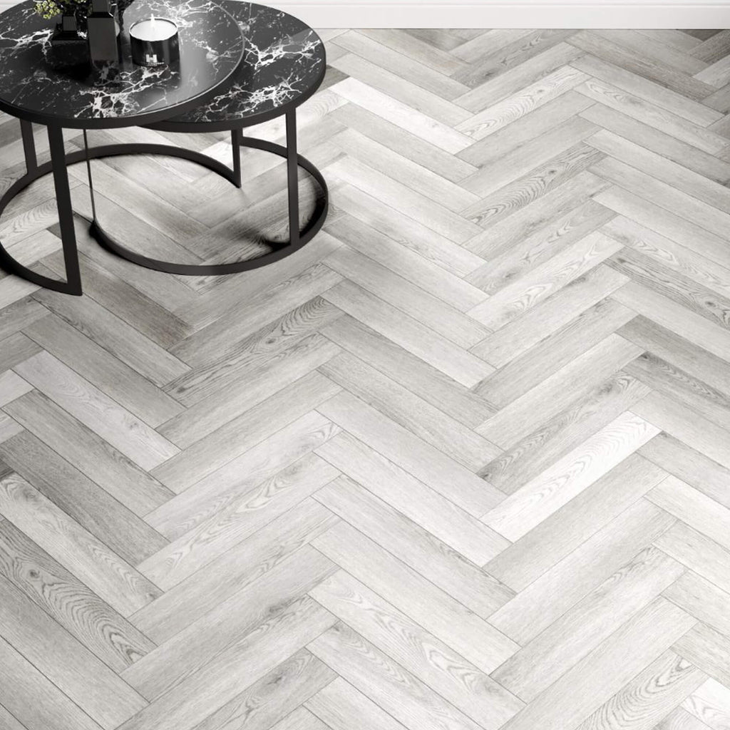 Pyrenees Oak Rigid LVT Herringbone Flooring and a round black table in the corner.