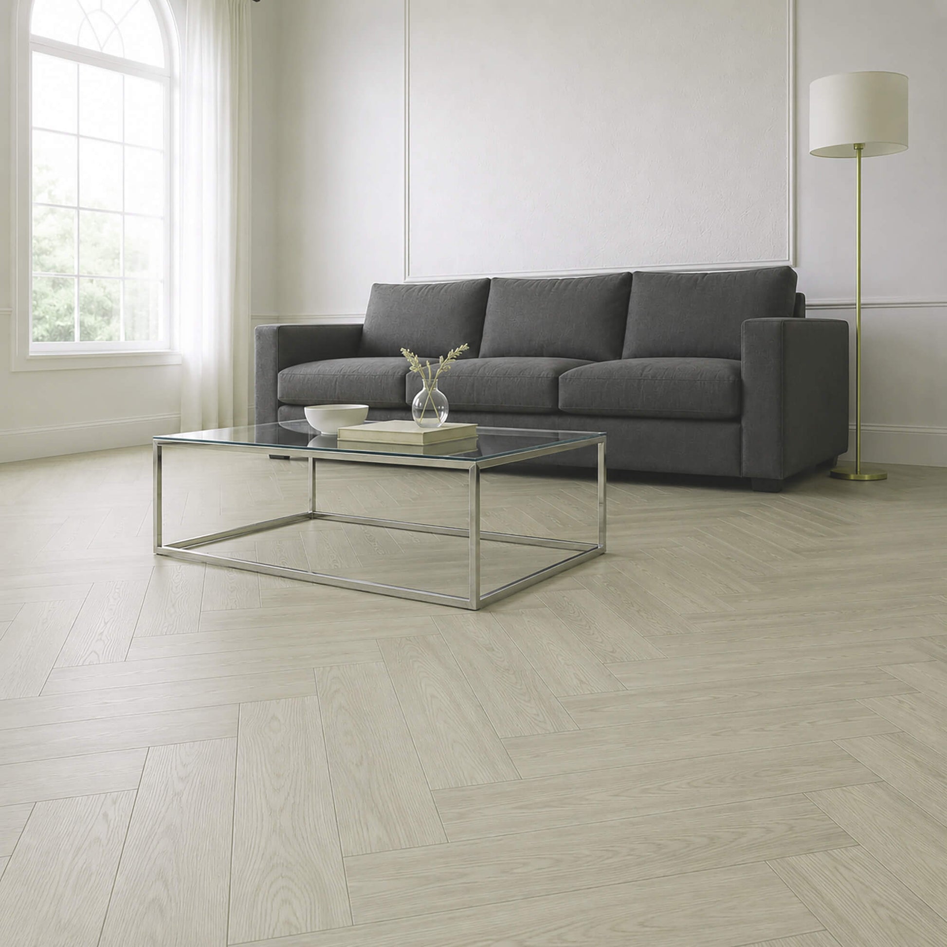 Modern living room with Siberian Oak Rigid LVT herringbone flooring, a grey sofa, glass coffee table, and white walls.