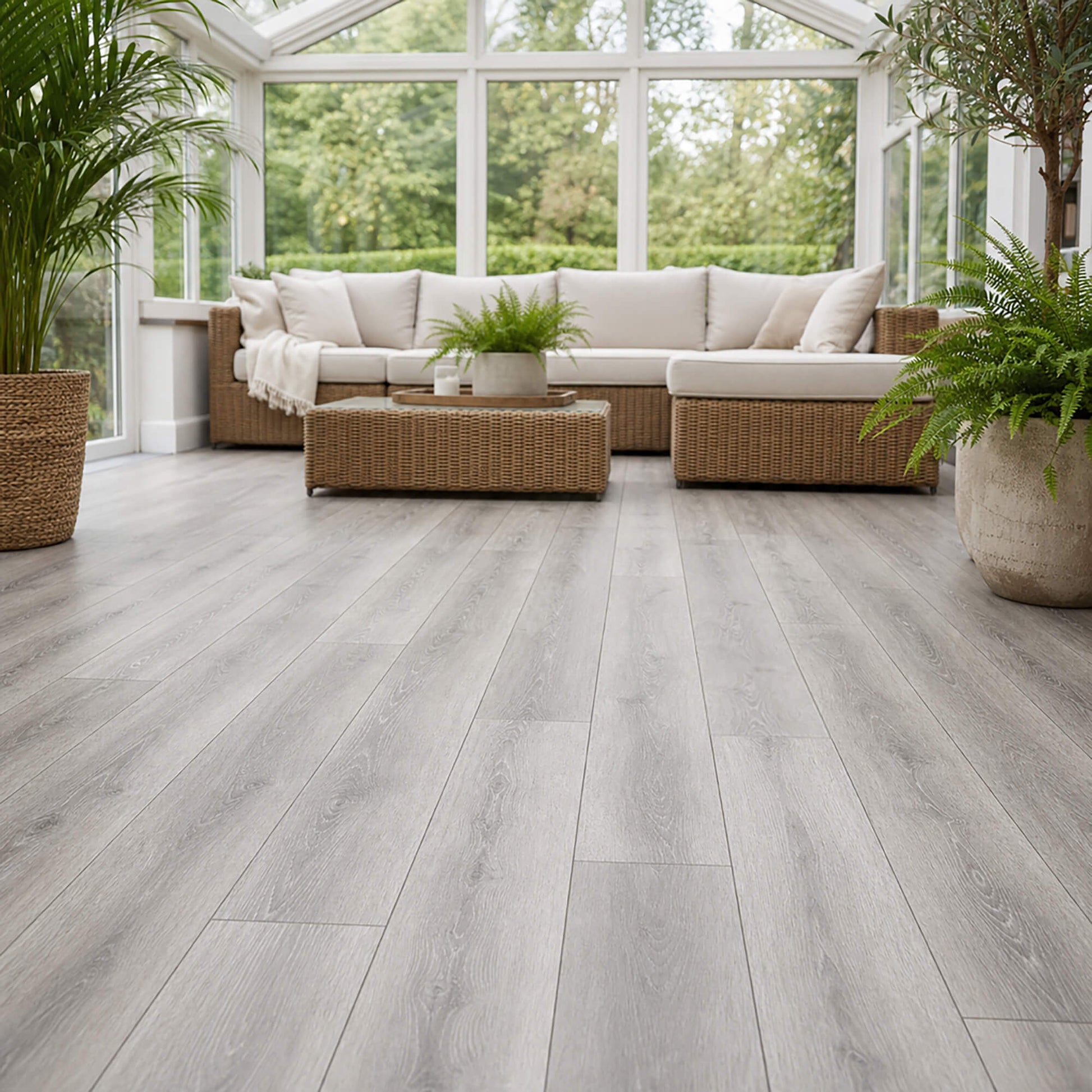 Modern home conservatory with wicker furniture and large windows with Silver Grey Oak Prestige laminate flooring.