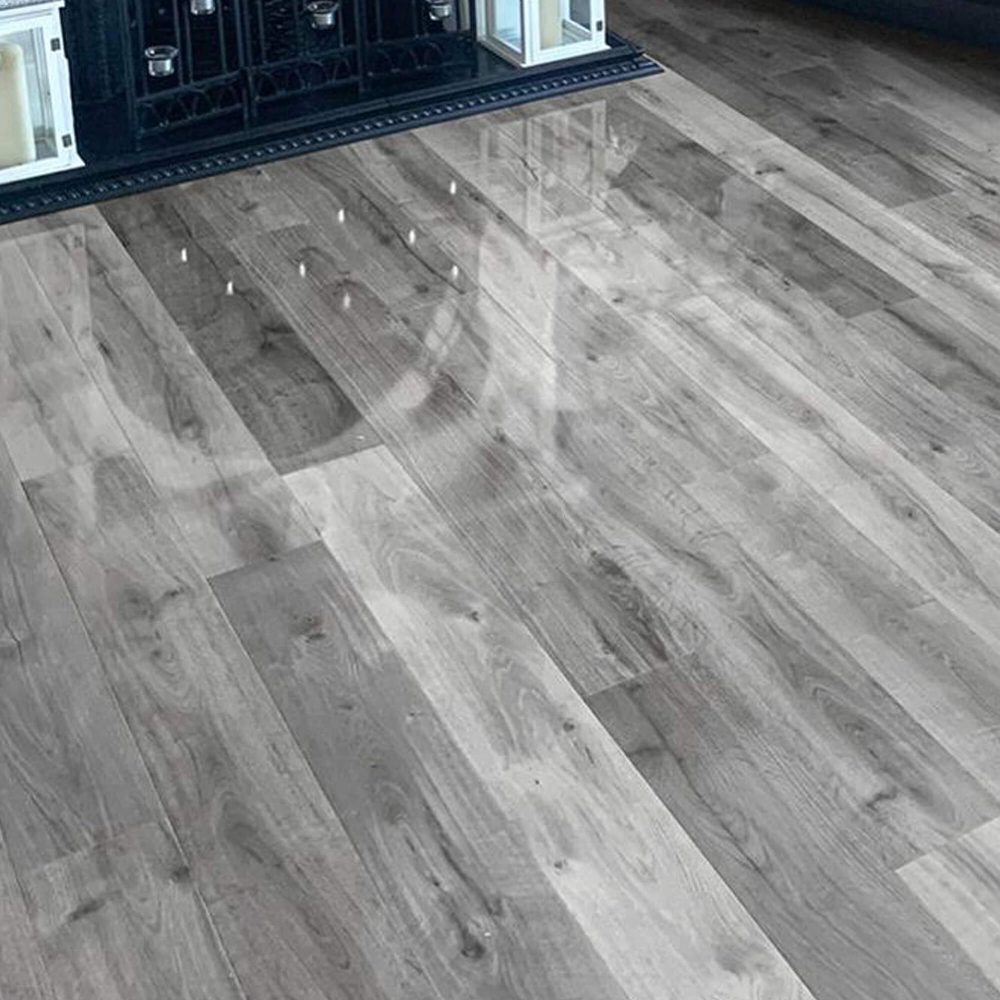 Uptown Oak Gloss Laminate Flooring in a living room setting with a fireplace I the background.