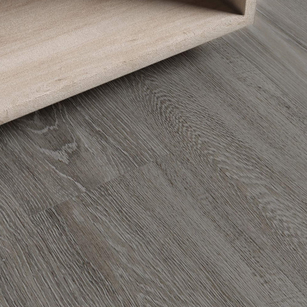 Close-up of Weathered Oak Rigid LVT flooring with a corner of  bedside furniture visible.