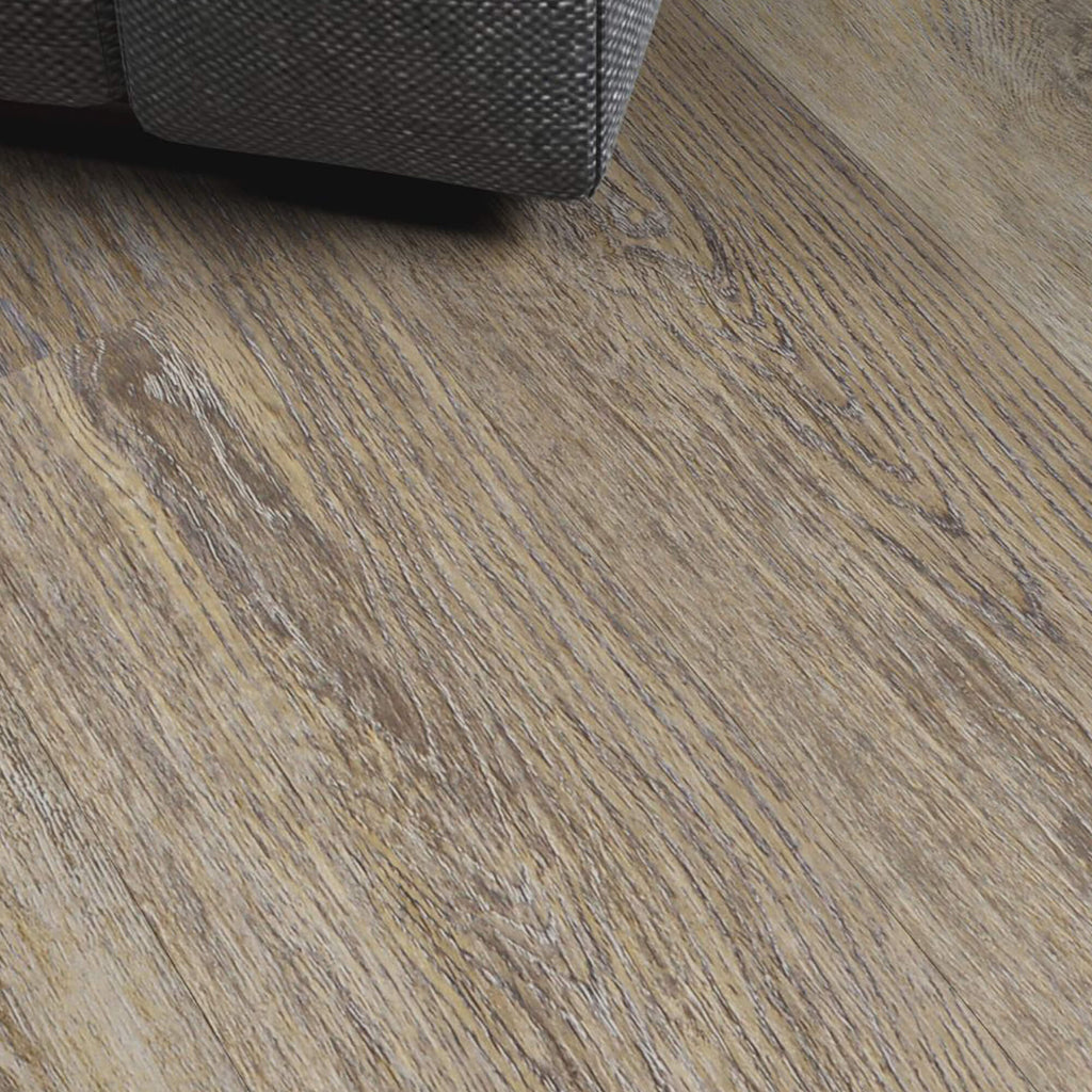 Close-up of Weathered Oak Prestige laminate flooring with the corner of a sofa in the background.